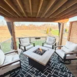 A covered patio featuring several chairs arranged around a cozy fire pit, ideal for gatherings and relaxation.