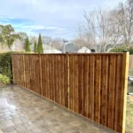 A wooden fence lines a brick walkway, creating a charming outdoor pathway.